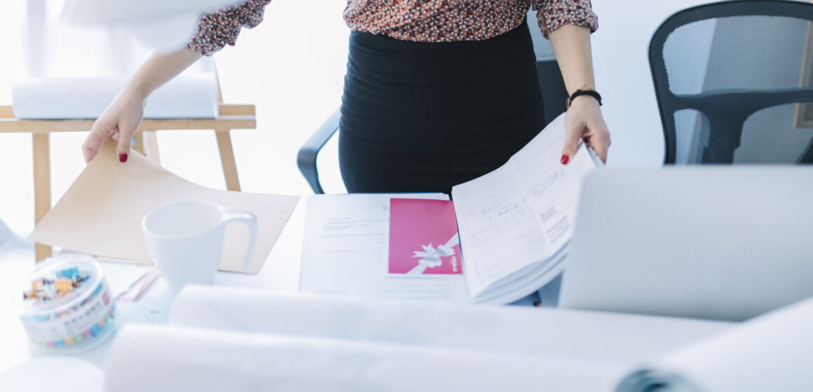 close-up-businesswoman-holding-opened-file-desk